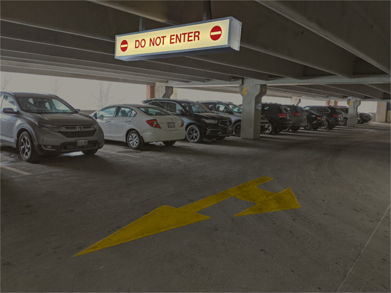 overhead illuminated signs show direction of travel. Pavement marking are bright orange arrows showing direction of travel